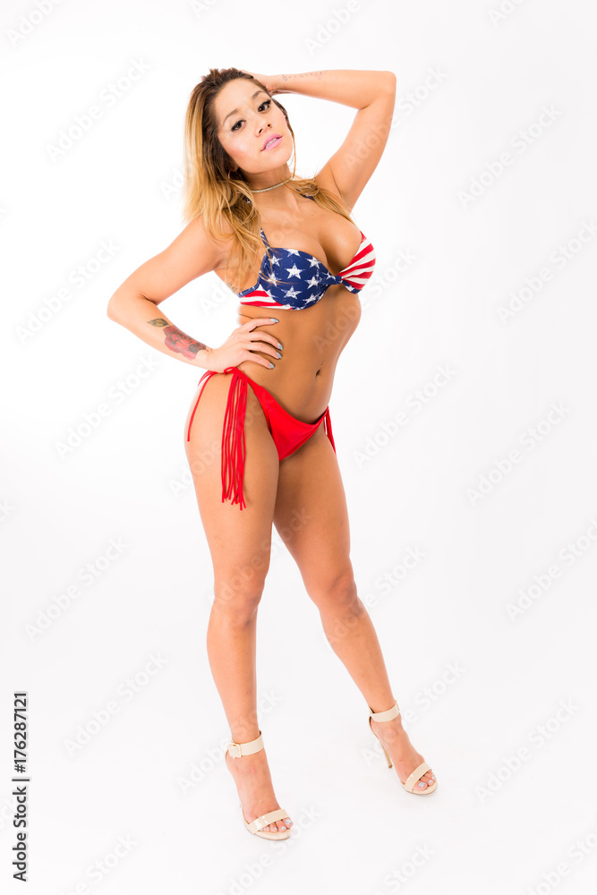 Young fit hispanic woman in American Flag patterned swimsuit posing on a white background Young fit hispanic woman in American Flag patterned swimsuit posing on a white background
