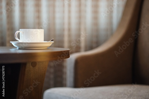 white coffee cup on the table by a sofa couch in hotel room