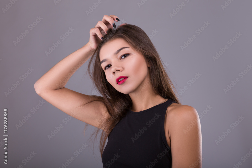 Fototapeta premium Brunette Woman with beauty makeup and red lips over gray background