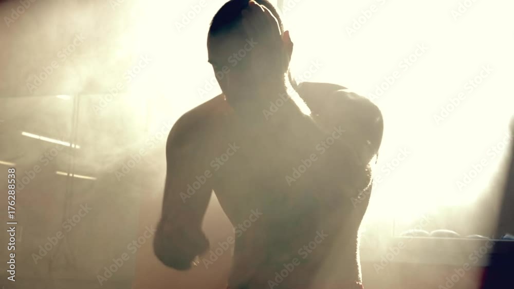 Silhouette strong boxer training and moving punching in gym slow motion black and white