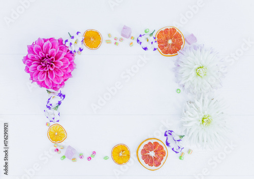 Frame of flowers and candy with dried oranges. Top view. photo