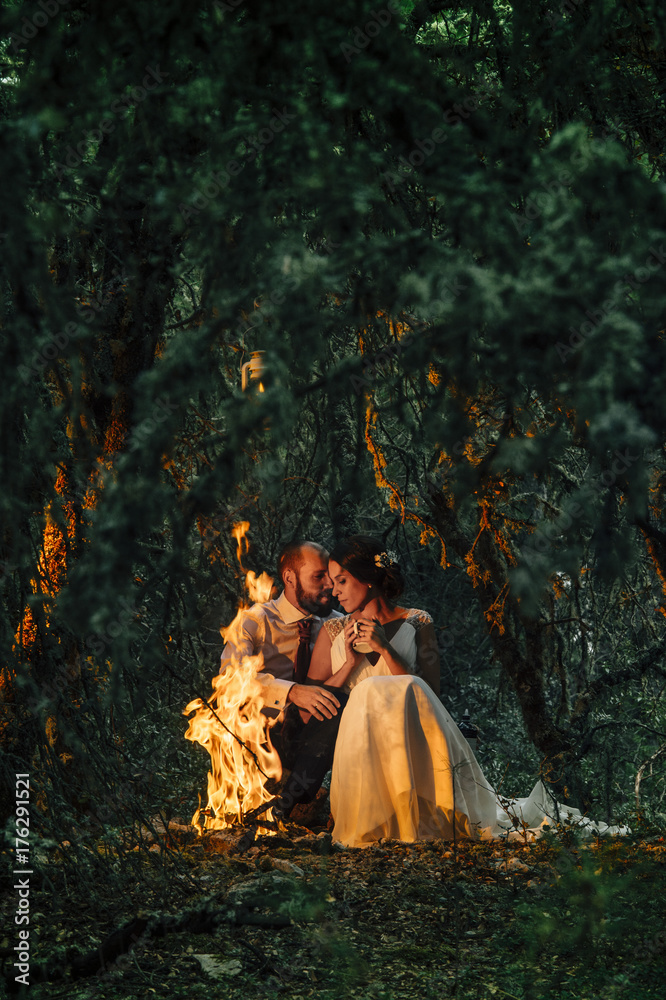 happy couple sitting on bench near camp fire happy couple sitting on bench near camp fire
