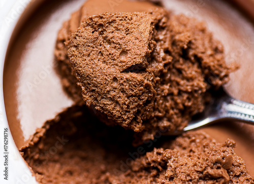 Chocolate Mousse in White Cup Bowl. Spoonful Visible  Spongy Texture with Pores. Vibrant Rich Brown Color. Macro Close up photo