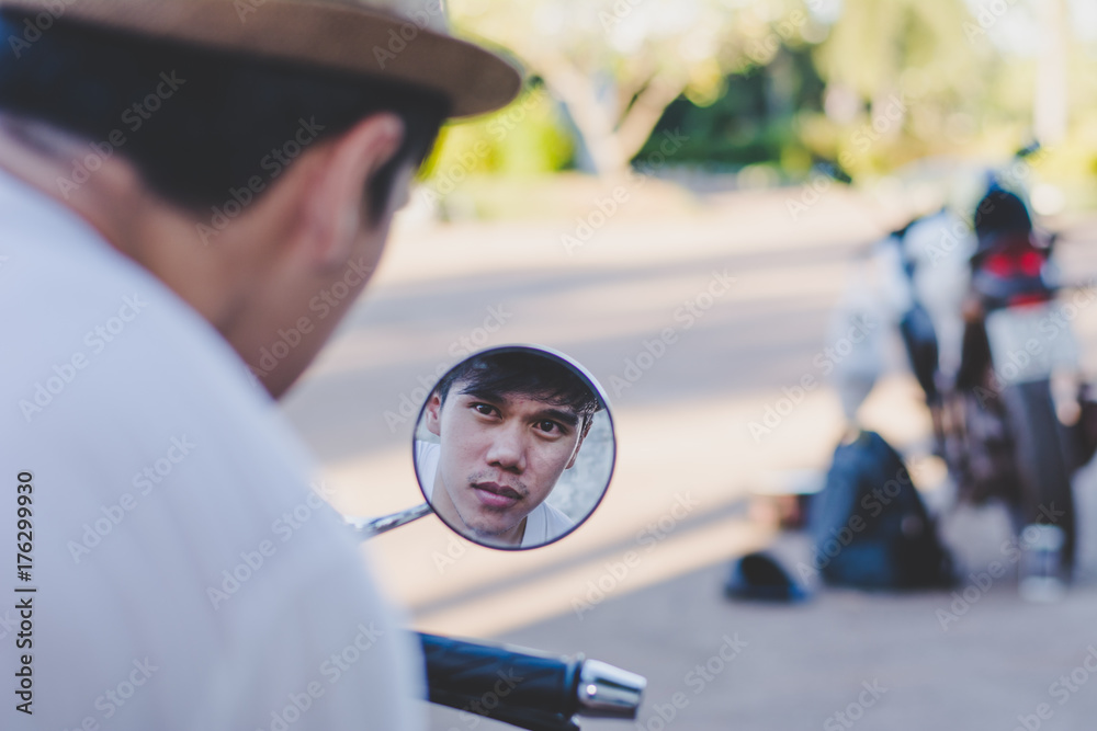Man rides on modern motorbike outdoors and looking at the mirror. Man rides on modern motorbike outdoors and looking at the mirror.