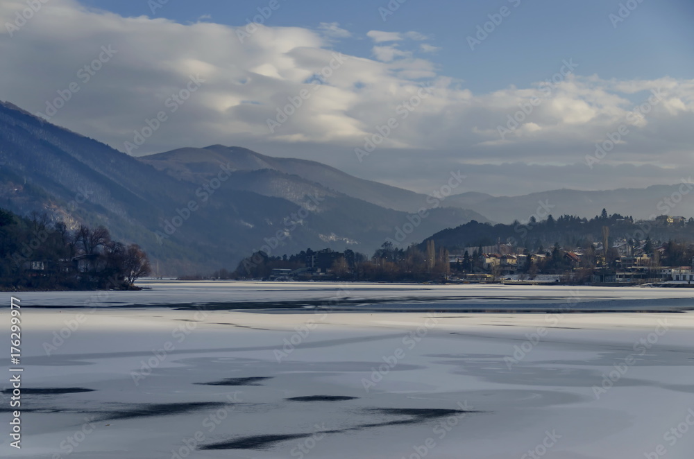 Scene with frozen lake, snowy mountain, glade, forest and residential district of bulgarian village Pancharevo, Sofia, Bulgaria 