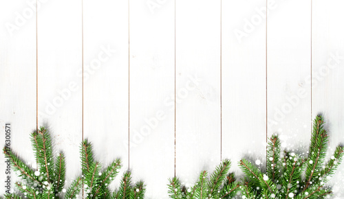 Christmas snow-covered branches on a white wooden background. New Year's background, holiday, christmas, snow, winter, green branches top view with copy space.