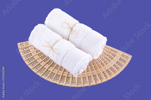 Spa. Two white towels rolled into a roll and a wooden fan on a blue background