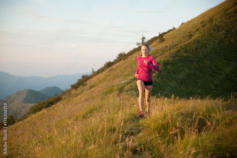 Woman runs on a top of the mountains with mountain range in background Woman runs on a top of the mountains with mountain range in background