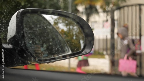 Elementary-school students return home after lessons. Students go home. meeting the child after school by car. 4k, slow motion. Drops on the car mirror .