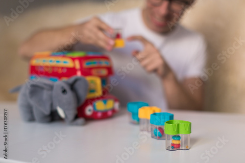 Close-up toys on the table with which young man playing indoors