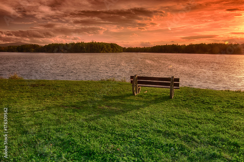 Bench on lake shore at sunset