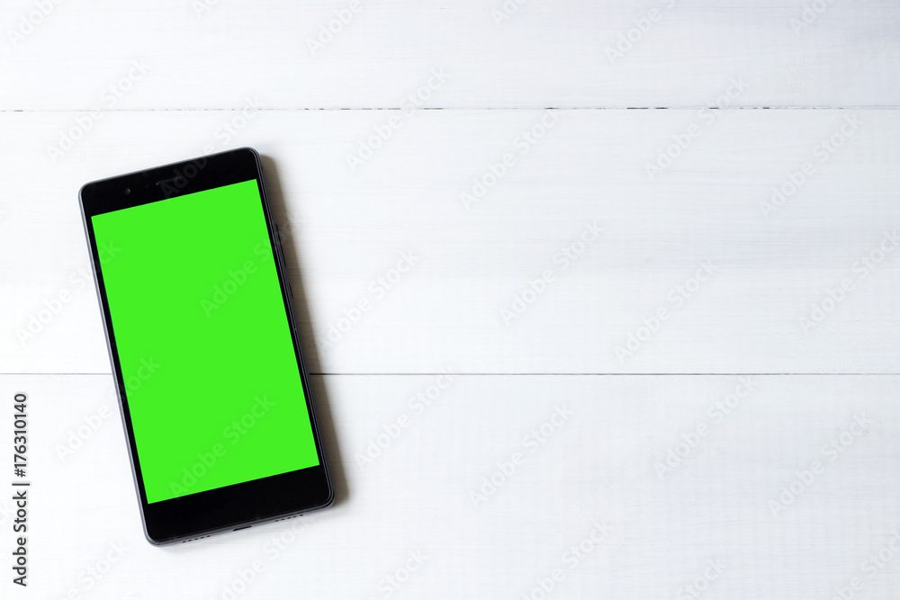 smartphone with green screen on wooden table