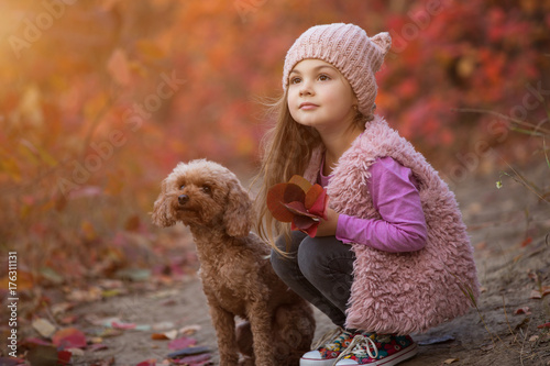 Little girl sitting with dog together on nature at the autumn day, art portrait