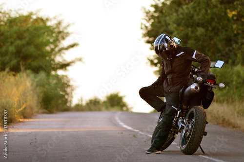 Lonely motorcyclist in helmet looking at the ground. Lyrical statement with a thoughtful motorcyclist. 