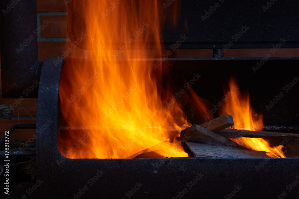 Fototapeta premium Burning firewood in the barbecue at backyard close up.