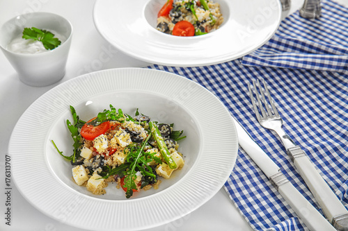 Plate with quinoa salad on table