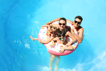 Happy family with inflatable donut in swimming pool