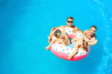 Happy family with inflatable donut in swimming pool