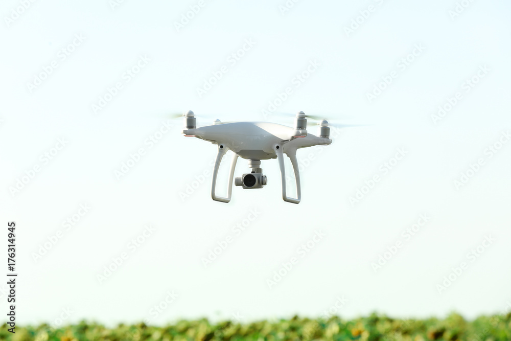 Modern quadcopter flying over field Modern quadcopter flying over field