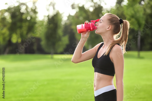 Sporty young woman drinking...