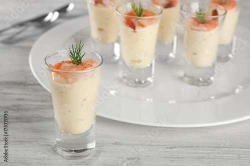 Glass of white sauce with shrimp on table