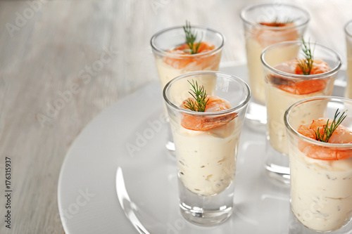 Plate with glasses of white sauce and shrimps on table, closeup