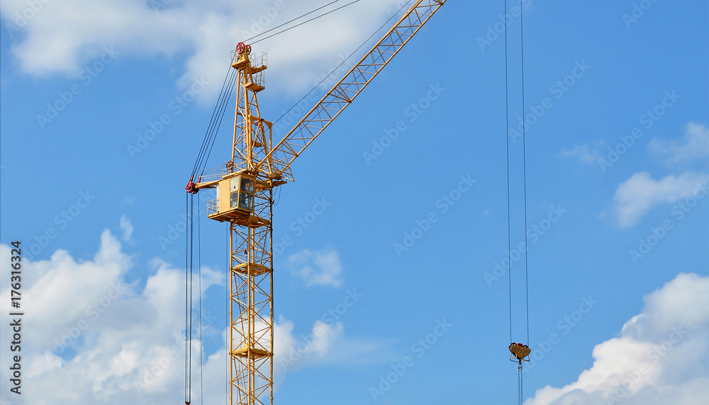 Construction site. Contemporary urban landscape. Big industrial tower crane with blue sky in background. Modern civil engineering. Beautiful photo of a construction crane against sky