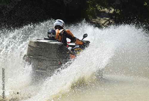 The man on the ATV crosses a stream photo