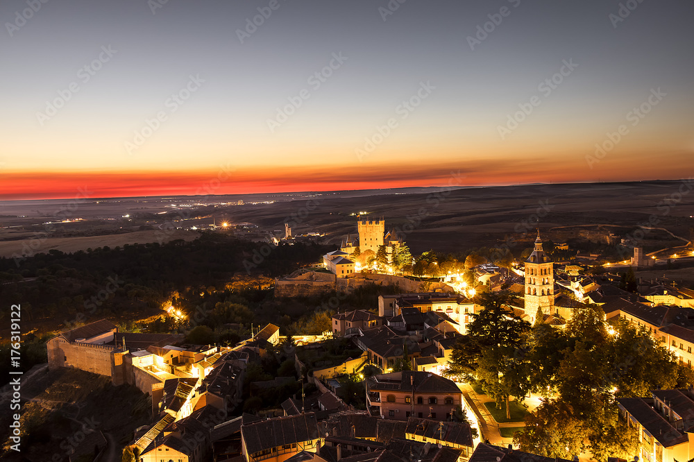 Aerial view of Segpovia at sunset in autonomous region of Castile and León, with iluminated buildings and Alcazar. Castle residence of kings in medieval epoch, Declared World Heritage Sites by UNESCO