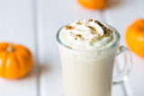 Pumpkin Spice Latte with Whipped Cream and Spices on a White Wooden Background and Small Tiny Pumpkins Close Up