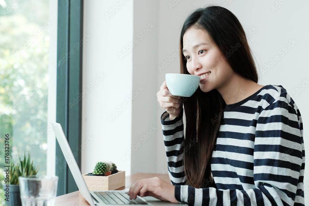 Young asian woman using laptop computer and drinking coffee at cafe background, people and technology, lifestyles Young asian woman using laptop computer and drinking coffee at cafe background, people and technology, lifestyles