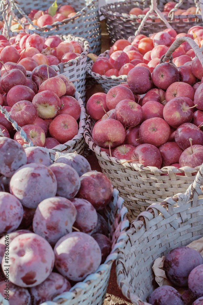plums and apples in baskets at the market plums and apples in baskets at the market