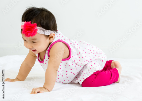 Portrait of adorable baby crawling on a white floor with head band