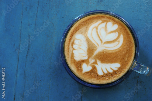 Top view of hot coffee latte cappuccino cup with beautiful latte art milk foam on blue painted wood table background.