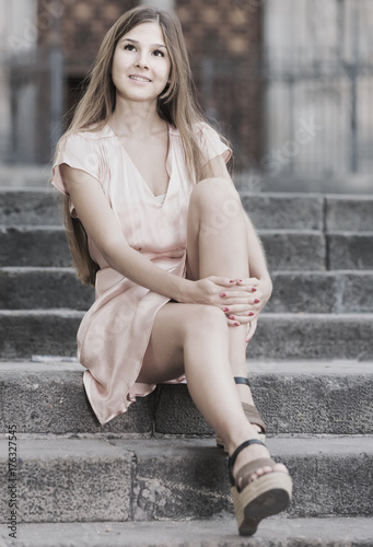 young  female in rose  dress sitting in city © JackF