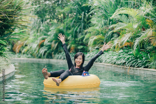 Fényképezés young woman enjoying tubing at lazy river pool