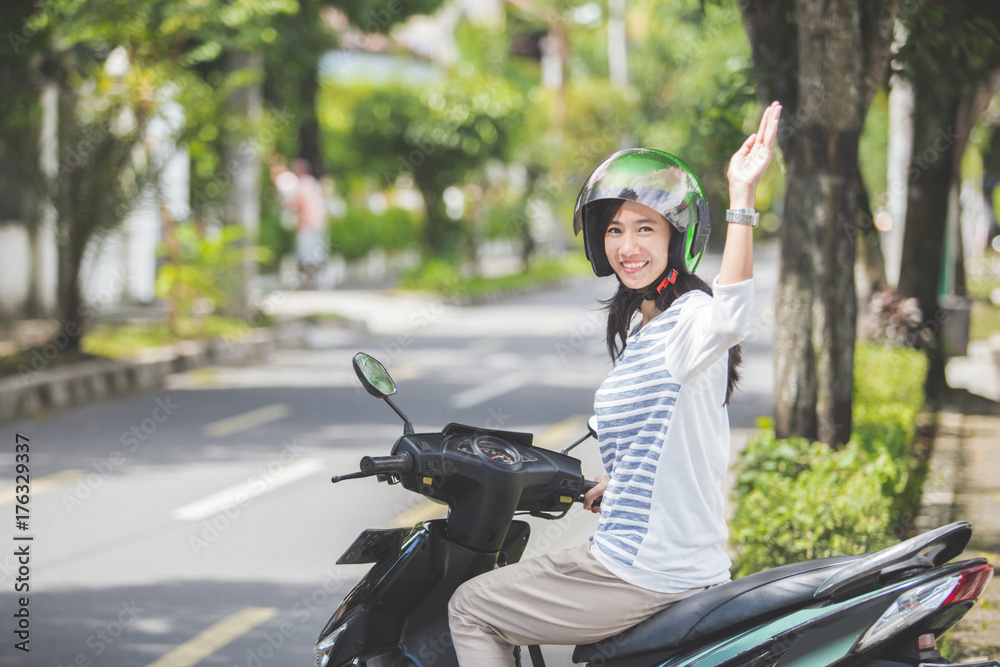 woman riding a motorbike and waving hand