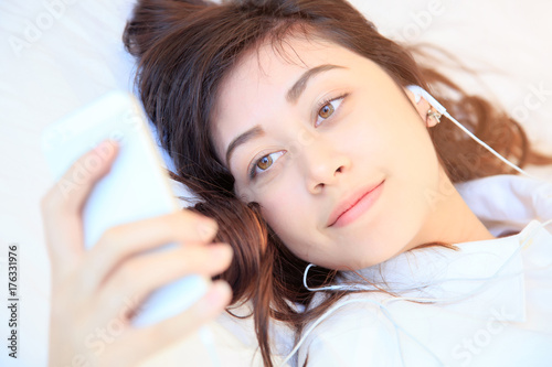 woman at home reading a text message from smartphone in her bright bedroom
