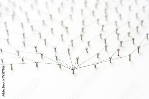 nails in white paper simulation network. linked together by black cotton