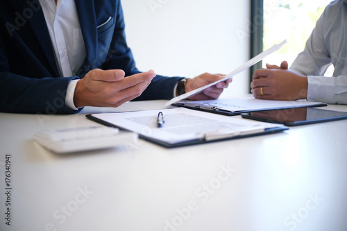 Sales manager giving advice application form document, considering mortgage loan offer for car and house insurance. photo