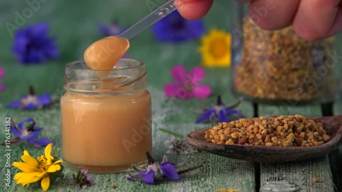 Raw organic royal jelly in small bottle and spoon pollen