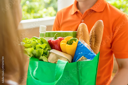 Grocery store delivey man  delivering food to a woman at home photo