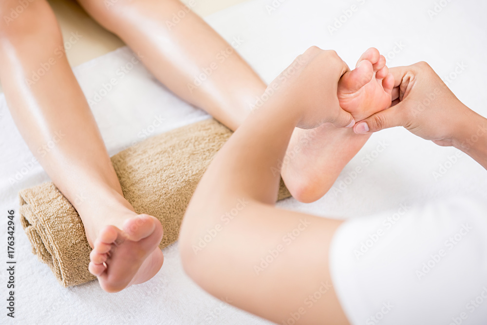 Therapist giving relaxing reflexology Thai foot massage treatment to a woman in spa