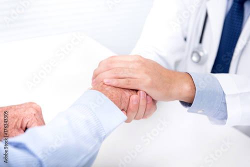 Fotografía Doctor comforting a senior patient by holding his hand