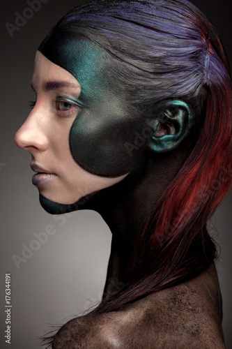 Portrait of a woman with creative make-up on a gray background. With bright colors on her hair and face. Art beauty.