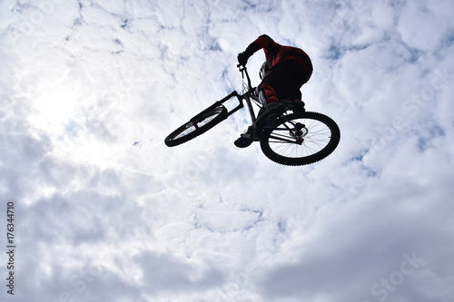 Silhouette of a young man freestyle stunt cyclist flying in the sky