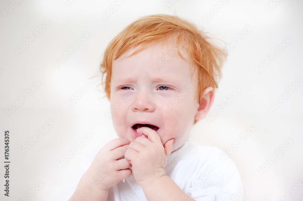 Miserable redhead boy crying on the white background Miserable redhead boy crying on the white background