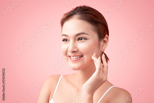 Portrait of Beautiful Skin care woman enjoy and relax touching her face on pink background