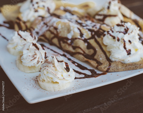 Pancakes with banana and whipped cream.