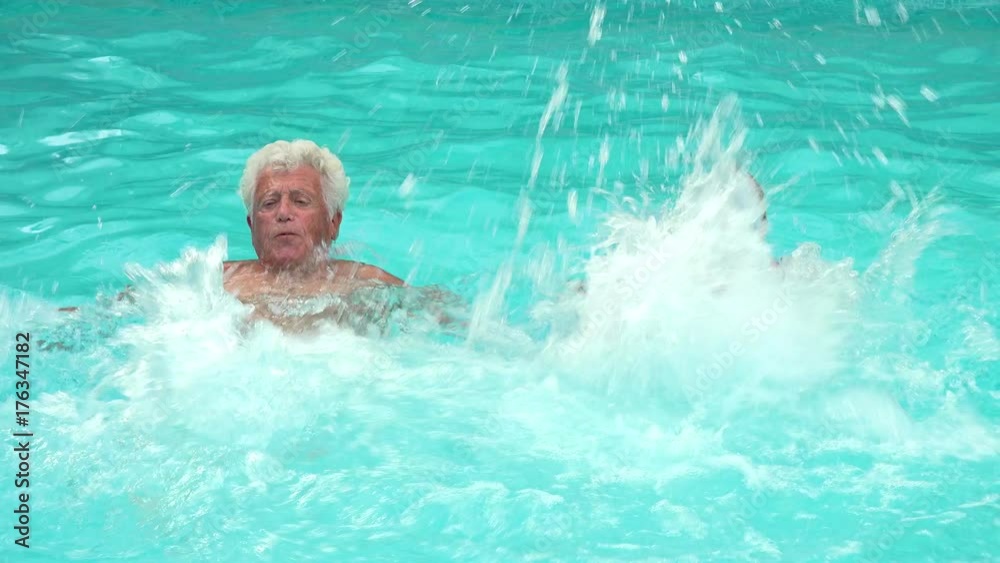 A mature couple playing with foam noodles in swimming pool A mature couple playing with foam noodles in swimming pool